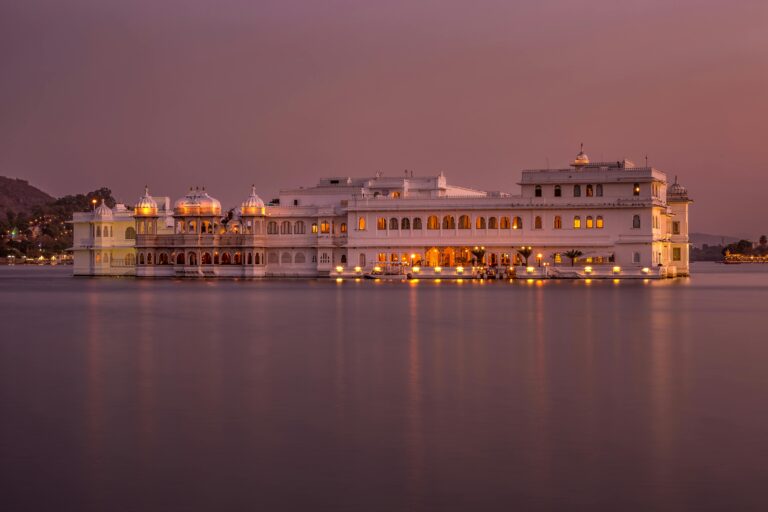 Stunning twilight view of Udaipur's Lake Palace illuminated, reflecting serene lake vibes.